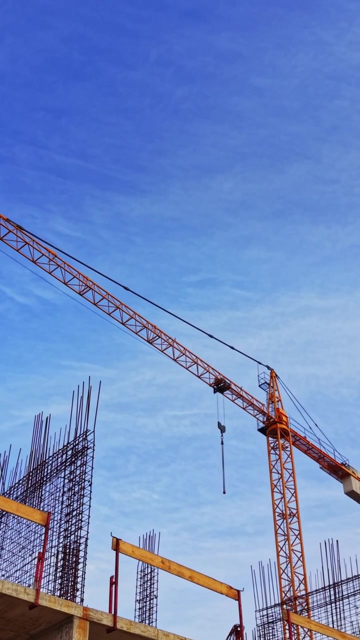 Construction site with crane and rebar against blue sky