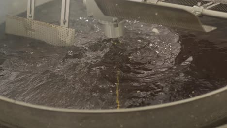 producción de papas fritas y bocadillos. máquina industrial de fritura profunda. las papas fritas se fríen en un cuenco grande con aceite. la línea de producción de la fábrica mueve las papas frias doradas después de freír.