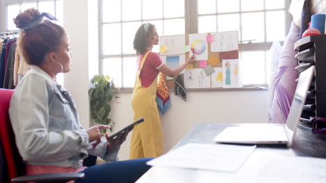 Diversas-Diseñadoras-De-Moda-Femeninas-Usando-Tabletas-Discutiendo-Diseños-En-El-Estudio,-Copiando-Espacio,-Cámara-Lenta