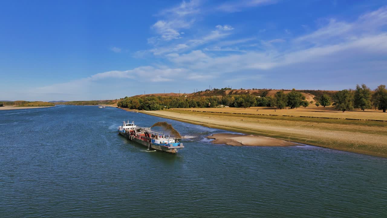 широкополосный взгляд на дноуглубитель, разгружающий песчинку на большой реке, солнечный день