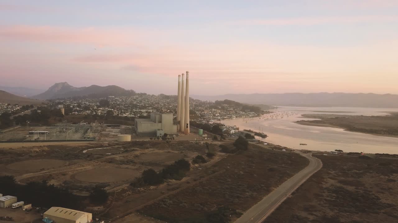 Morro Bay - California, USA. Cinematic sunset aerial flyover with push in towards shoreline industry. Filmed on DJI Mavic Pro