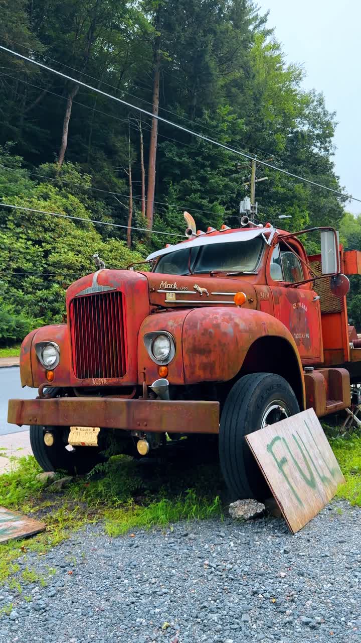 Jim Thorpe, USA, 2 July 2025: Rusty vintage red Mack truck parked on gravel. An old abandoned red Mack truck with rust and a "Full" sign resting against the front tire