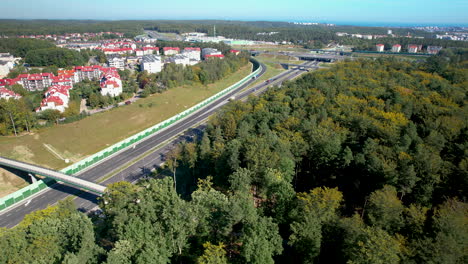 aerial orbit around multi lane highway below suburban apartment complex and dense forest