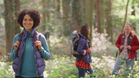 portrait of woman with group of female friends on camping holiday hiking in woods together