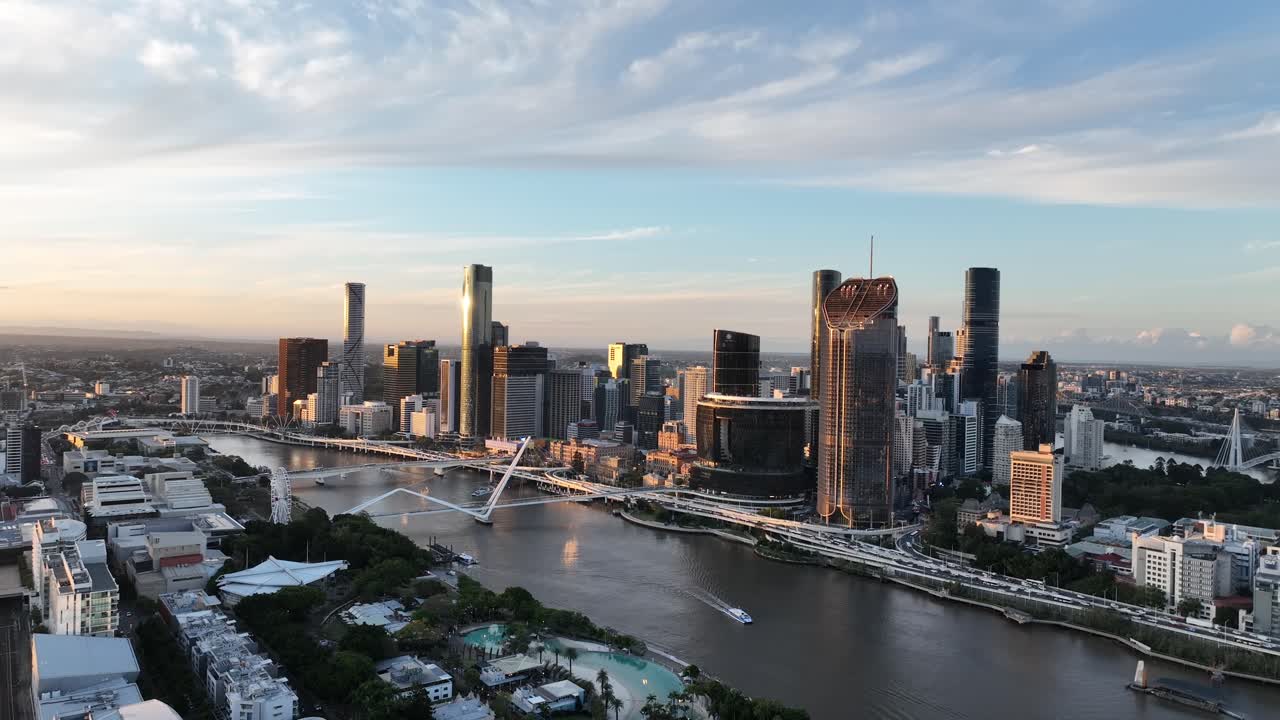 Langsom dronedrift i den gyldne time over Brisbane-floden, der viser South Bank og CBD's skyline med glødende Queens Wharf og The Star Brisbane-tårne, Brisbane, QLD, Australien