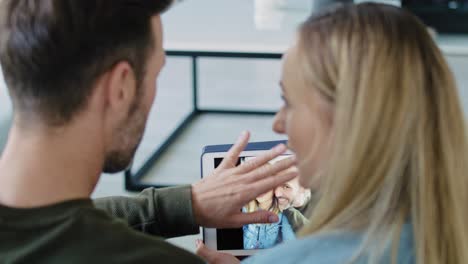 Vista-Trasera-De-Una-Pareja-Madura-Con-Tablet-En-El-Salón