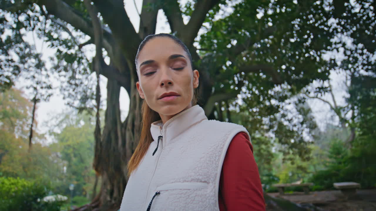 retrato mujer deportiva mirando cámara preparándose para la rutina de entrenamiento en el parque verde