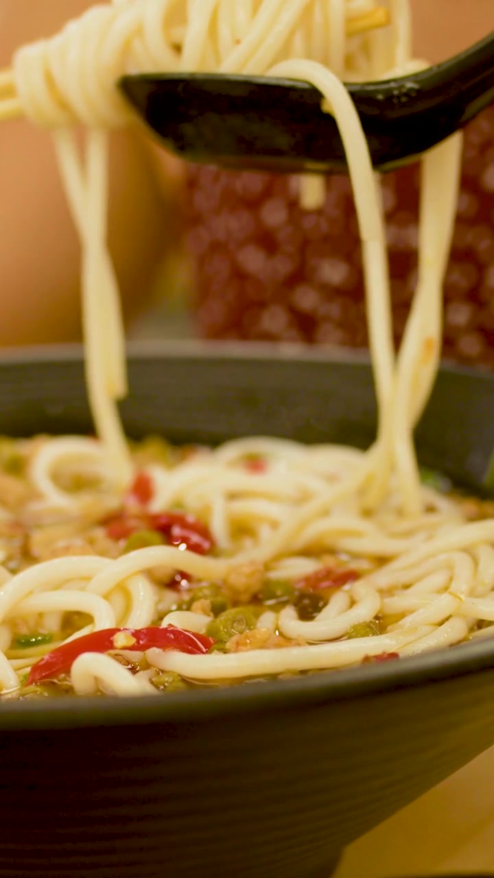 Primo piano di deliziosi noodles piccanti sollevati da una ciotola