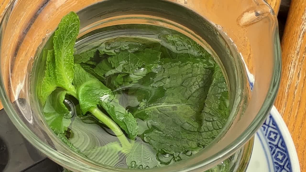 Fresh mint tea leaves in small glass teapot hot drink