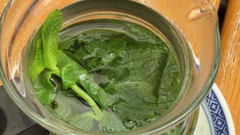 fresh mint tea leaves in small glass teapot hot drink