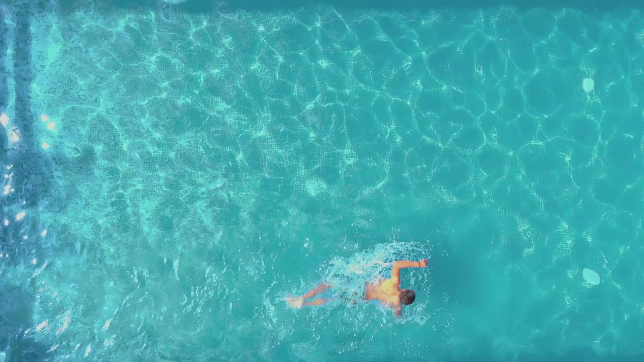 Pemandangan pria berenang di kolam renang hotel.