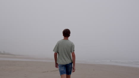 teenager walking on a foggy beach