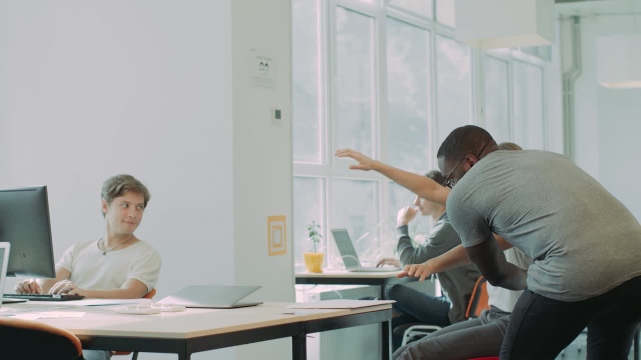 gente feliz rodando en sillas en el coworking. hombre alegre abrazando a una mujer sonriente.