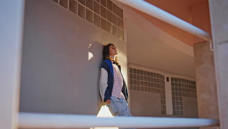 estudiante relajándose en la calle de la noche cerca del edificio. mujer apoyada en la pared de la ciudad