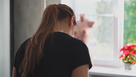 seamstress measures details with tape against window in room
