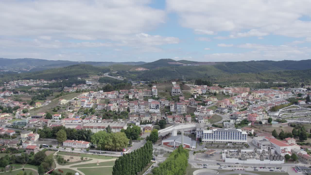 Luftfoto af en lille by i det nordlige Portugal med beboelsesejendomme og bølgende bakker