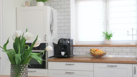 Slider-shot-of-a-bunch-of-white-tulips-kept-in-a-glass-vase-in-the-modern-kitchen-setup