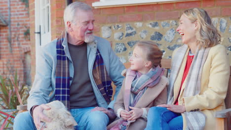 grandparents with granddaughter and pet dog outside house getting ready to go for winter walk