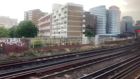 mirando por la ventana de un tren con vías férreas en una ciudad