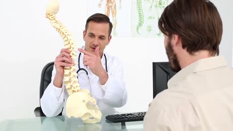 Doctor-showing-his-patient-a-model-of-a-spine