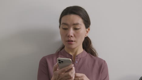 nervous female candidate wearing suit in office waiting for job interview looking at mobile phone