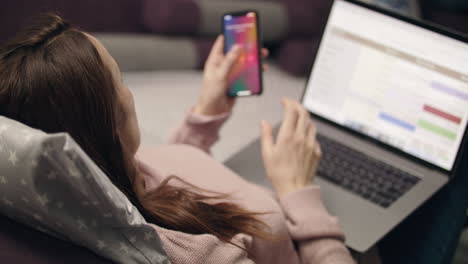 Woman-talking-mobile-phone-and-working-on-laptop-at-home