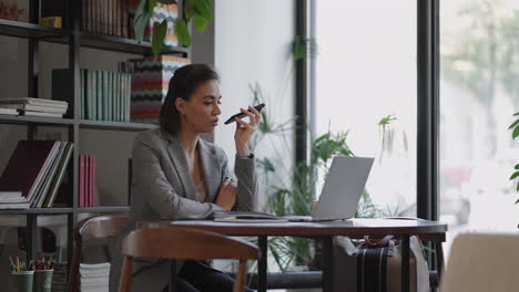 stylish young woman uses a smartphone surf the internet sitting at a table in modern cafe smiling. young business woman indoors in office using mobile phone