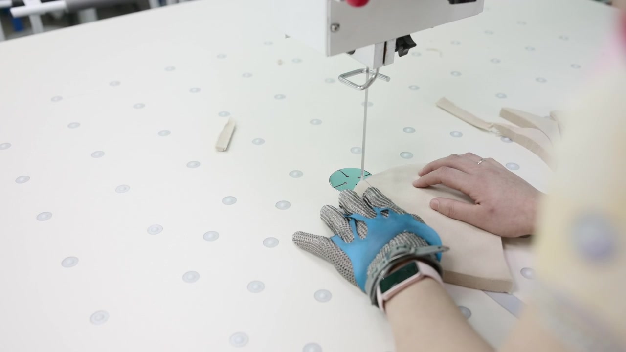 Closeup Industrial Sewing Machine Hands Guiding Fabric Across Perforated Worktable, Blue Protective Glove . Media