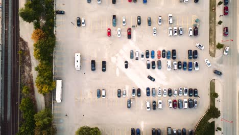 overhead top down aerial drone shot of a light grey cement parking lot full of colorful cars and people walking in a outdoor shopping center in winnipeg manitoba