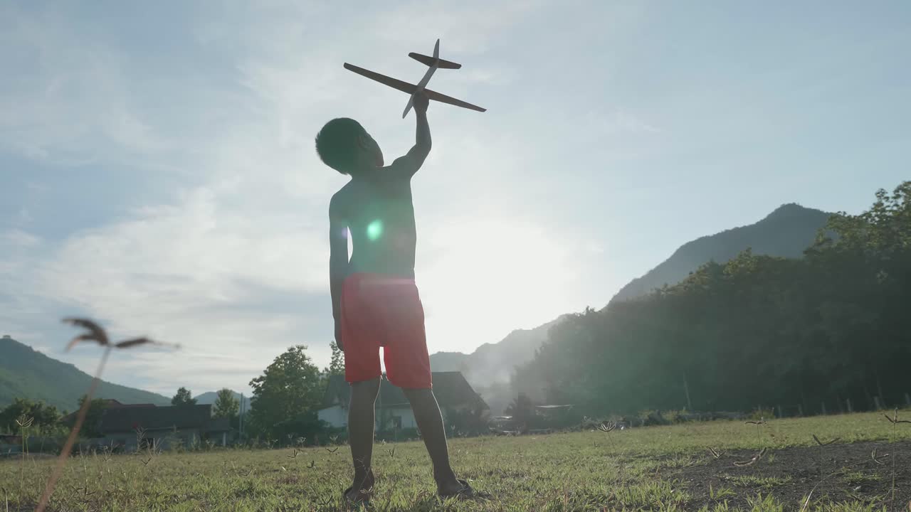 A boy playing with a toy airplane in a field
