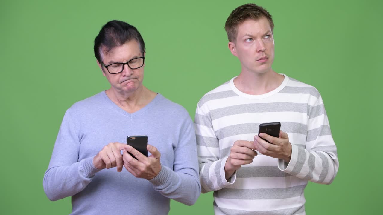 Senior handsome man and young handsome man using phone together