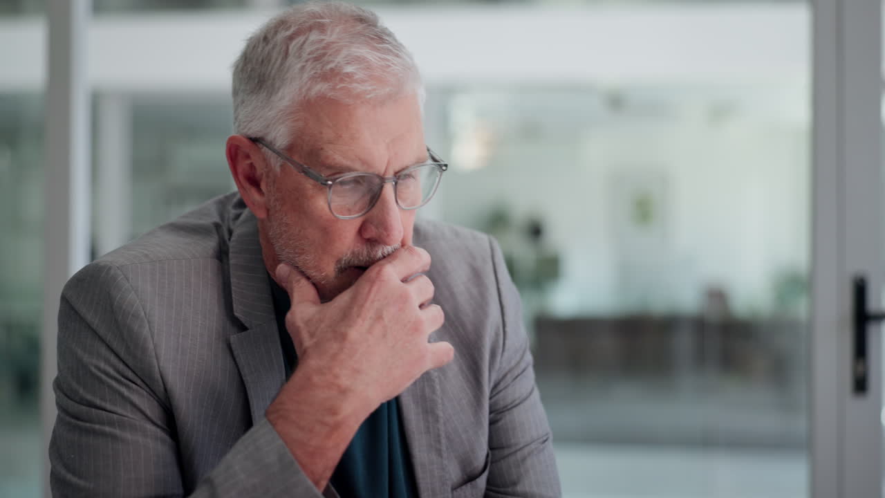 Senior Businessman Thinking While Working on Laptop in Office