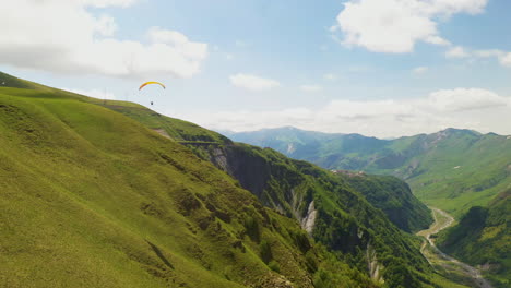 amplia toma de parapente volando en las montañas del cáucaso en gudauri georgia girando y revelando el valle