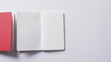 primer plano de libro rojo cerrado y libro en blanco abierto con espacio de copia en fondo blanco en cámara lenta