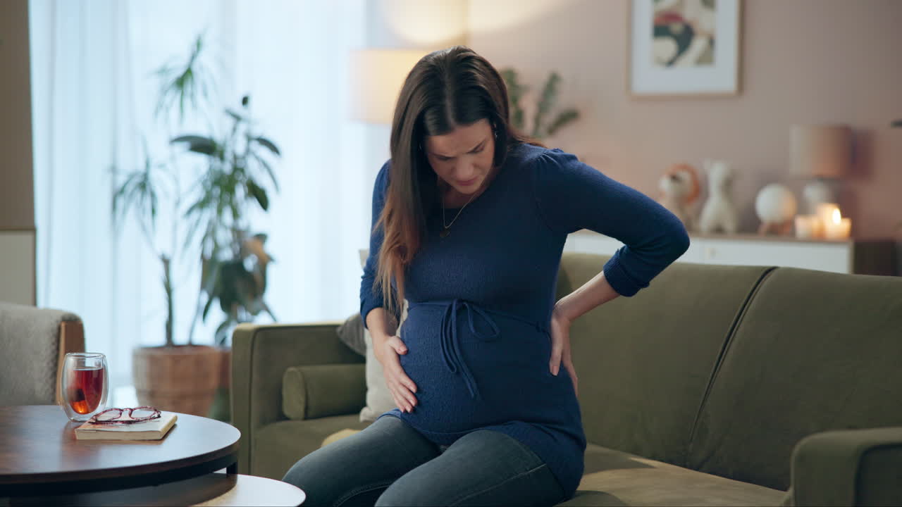 Pregnant woman experiencing back pain at home