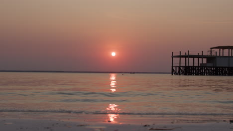 sunset over the ocean with a pier