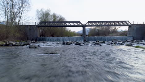 un dron cercano y rápido disparó sobre un río frente a un puente, 4k uhd