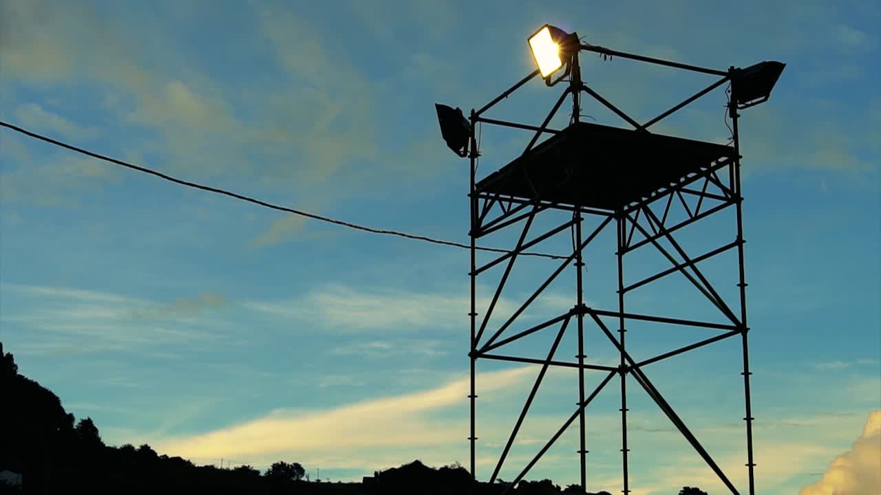 황혼의 하늘 뒤에 있는 스포트라이트의 영상을 닫으세요.