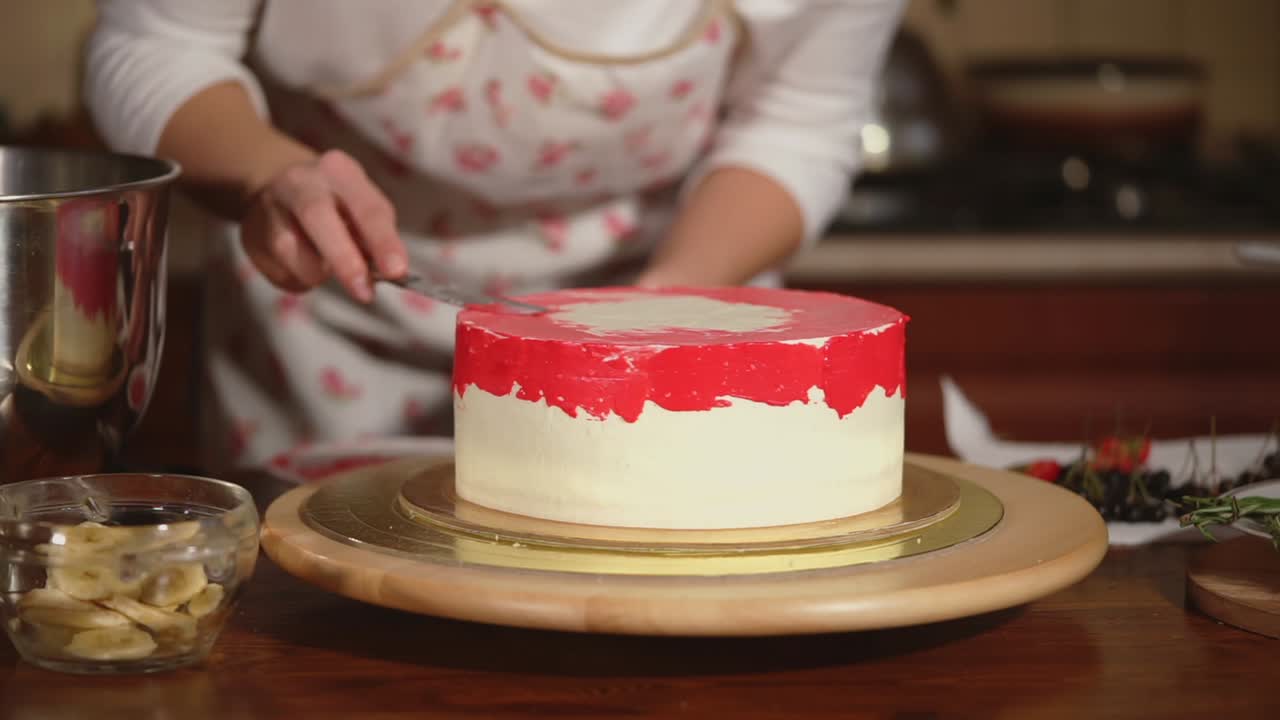 Donna che decora una torta rossa e bianca