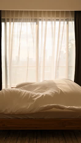 empty bed with white bedding in a bright bedroom with curtains