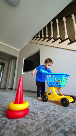 lovely baby boy takes the details of the toy from the cart. cute kid builds a pyramid on the floor. low angle view. vertical video.