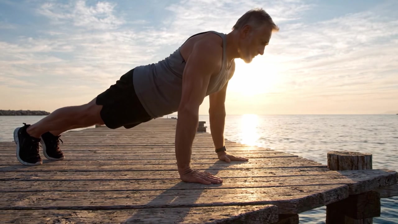 A determined individual performing push-ups on a wooden pier at sunset, showcasing strength, discipline, and dedication to fitness amid a serene waterfront backdrop.