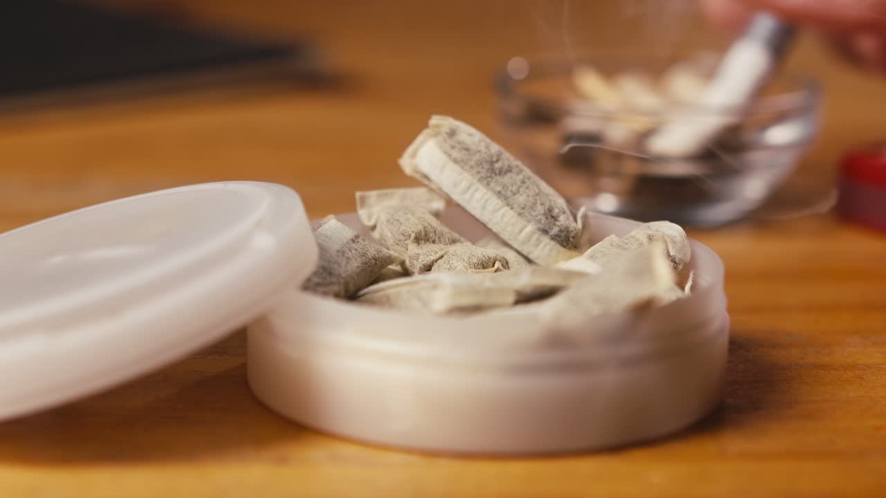 Snus nicotine tobacco close up, pack of tobacco for gum. unhealthy addiction. Man opening box with snus and taking one.