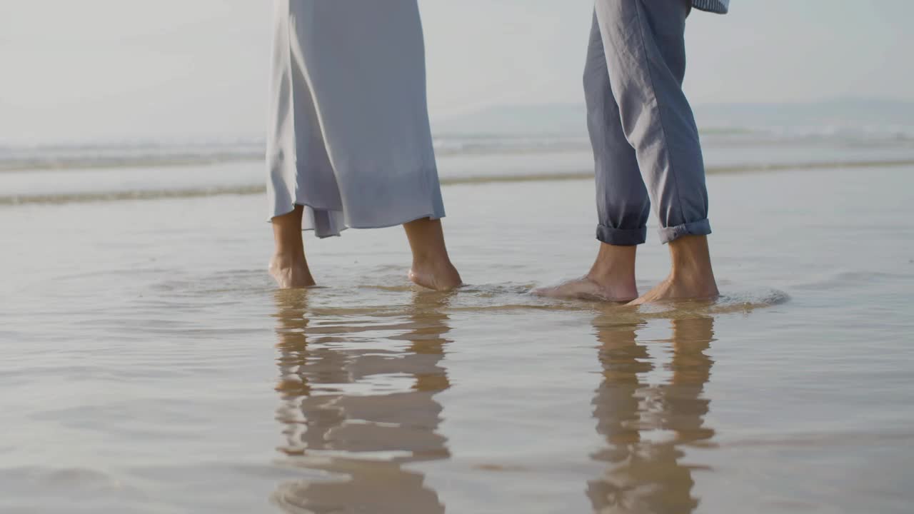 piernas de primer plano de una pareja caucásica bailando en la orilla del mar por la noche.
