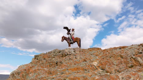 eagle hunter at the top of cliff in western mongolia - drone shot