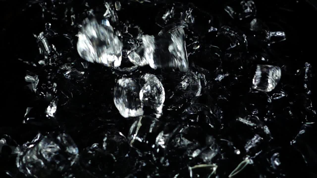 Caduta di cubetti di ghiaccio su sfondo nero. Rallentatore.