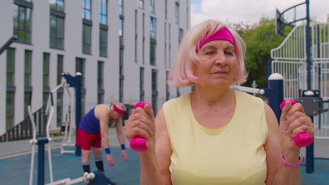 mujer anciana abuela atleta haciendo ejercicios de levantamiento de pesas de rutina con pesas en el patio de recreo