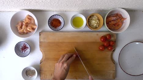 overhead video in bright colorful kitchen, male hand cutting chorizo into pieces