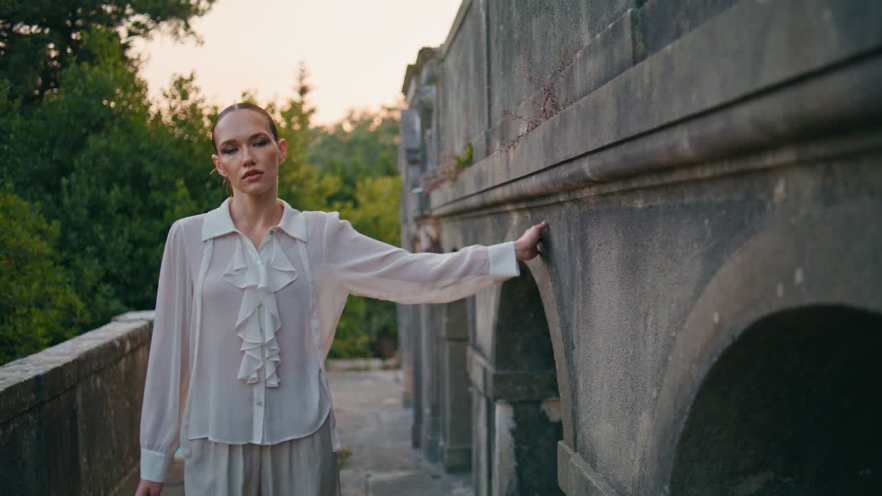 오래된 벽을 만지는 여인 산책 테라스 버려진 성. 발코니를 산책하는 여성