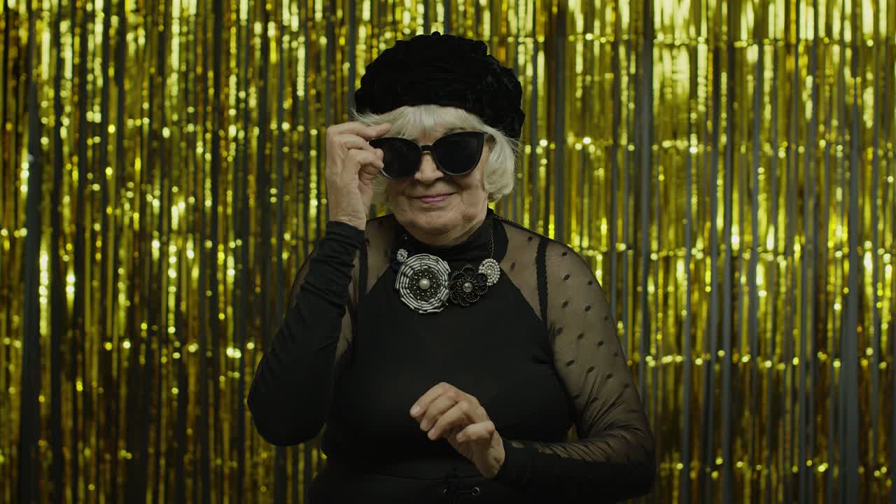 Elderly stylish grandmother. Caucasian woman posing on golden background
